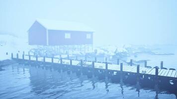 schneebedeckt Haus auf ein alt hölzern Seebrücke im das norwegisch Meer video