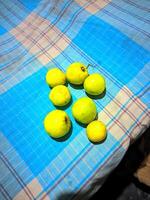 a group of green apples sitting on a blue and white checkered table cloth photo