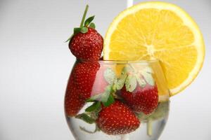un vaso de agua con fresas y un naranja rebanada foto