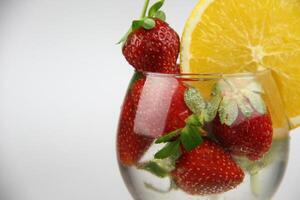 un vaso de agua con fresas y un naranja rebanada foto