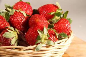 un cesta de fresas en un de madera cortar tablero en blanco antecedentes foto