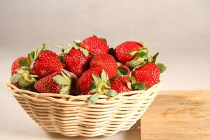 a basket of strawberries on a wooden cut board on white background photo