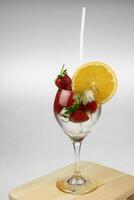 a glass of water with strawberries and an orange slice photo