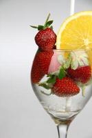 a glass of water with strawberries and an orange slice photo