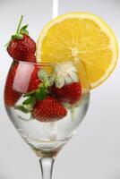 a glass of water with strawberries and an orange slice photo