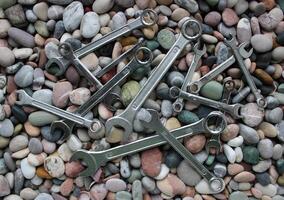 Mechanical wrenches of different sizes lying in disarray on stones photo