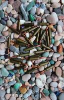 A bunch of live ammunition is thrown out of the magazine onto small pebbles photo