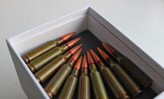 Machine gun bullets lined up with heads to heads in white case photo