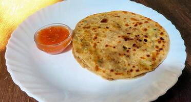 Aloo parantha an ideal indian breakfast served with tomato sauce photo