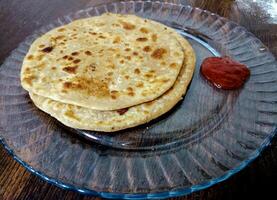 Aloo parantha an ideal indian breakfast served with tomato sauce photo