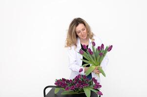 un dulce niña recogido un ramo de flores de diferente variedades de tulipanes soportes en un blanco antecedentes foto