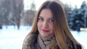 Portrait. Fashionable beautiful girl smiles beautifully against the winter forest in the park. A beautiful portrait. video