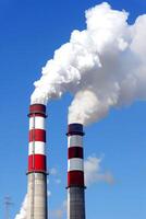 AI generated Industrial smokestacks emitting white smoke against a clear blue sky photo