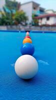 ai generado vistoso piscina pelotas en un línea en un azul mesa foto