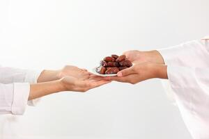 Female Muslim Hand Over A Plate of Dates Fruit to Other. photo