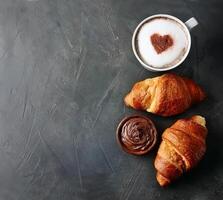 dos francés cuerno con caliente capuchino foto