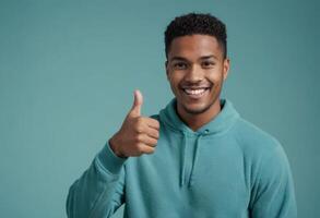 ai generado un alegre hombre en un verde azulado capucha da un pulgares arriba, sonriente en general. foto