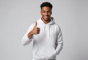 AI Generated A cheerful young man in a white hoodie giving a thumbs up. His engaging smile suggests confidence and friendliness. photo