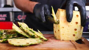 hand in gloves cutting slice of pineapple with knife video