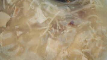 Bowl of chicken noodle soup on a wooden table video