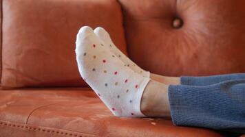 ein Person ist Verlegung auf ein Couch mit ihr Füße oben und tragen Weiß Polka Punkt Socken video