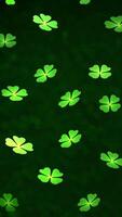 Looping animated vertical background of falling four-leaf clovers on a blurred green background. video