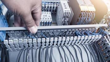 an electrician's hand is opening or closing the circuit cable cover on the electrical control panel board.Check and repair electrical trouble concept. photo