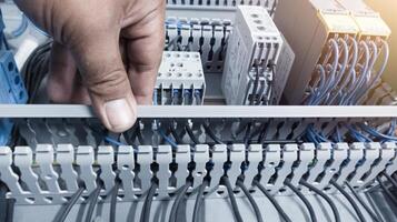 an electrician's hand is opening or closing the circuit cable cover on the electrical control panel board.Check and repair electrical trouble concept. photo