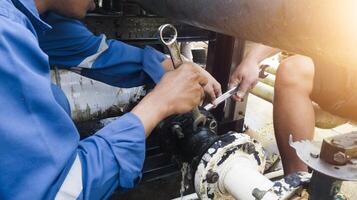 the mechanics are installing and tightening the rubber hose bolts on the cold water pipe connection. photo