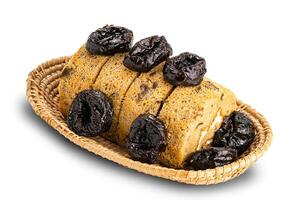 High angle view of prune sponge cake roll and dried pitted prune in bamboo basket on white background with clipping path. photo