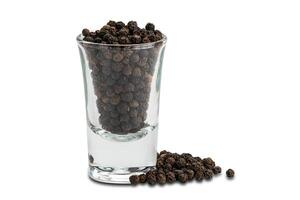 Side view pile of black pepper seeds and black peppers seeds in small glass on white background with clipping path photo