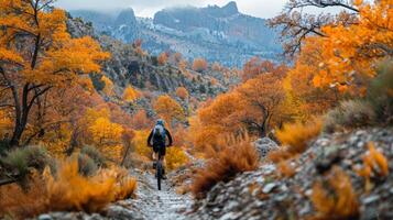 ai generado ciclista montando mediante un escabroso montaña camino, con vibrante otoño follaje creando foto