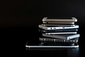 AI generated A pile of different smartphones isolated on a black background. photo