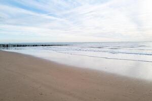 lonely beach with waves and sky in zeeland, the netherlands photo