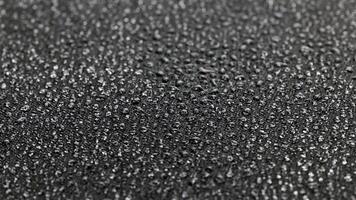 Filatura avvicinamento sfondo di nero idrofobo tessuto coperto con acqua gocce video