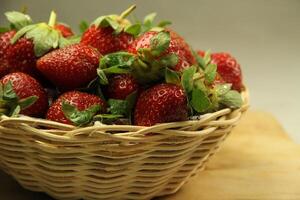 un cesta de fresas en un de madera cortar tablero en blanco antecedentes foto