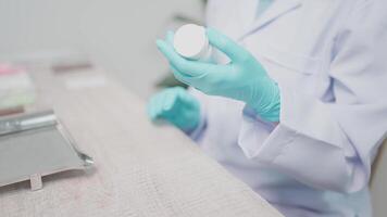 Female doctor checking the label of an asthma inhaler She is checking medication information on a digital tablet. Professional sitting at a table in a brightly lit doctor's office. video