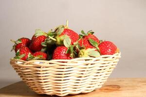 un cesta de fresas en un de madera cortar tablero en blanco antecedentes foto