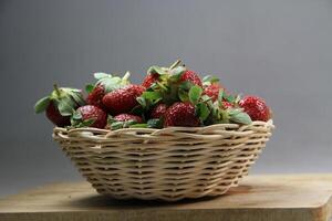 un cesta de fresas en un de madera cortar tablero en blanco antecedentes foto