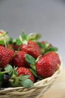 a basket of strawberries on a wooden cut board on white background photo