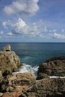 rock formation at the beach. rough wave and clear blue sky photo
