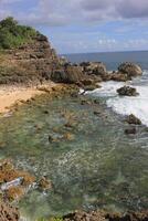 rocky beach. beach with many rocks and corals. blue sky background and rough wave photo