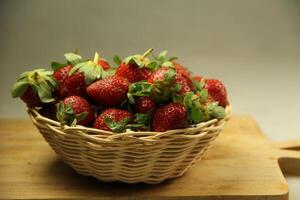 a basket of strawberries on a wooden cut board on white background photo