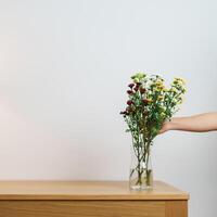 Woman hand arrange Colorful flowers bouquet in mason jar on table background. Happy day with fresh flower photo