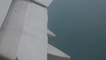 view to plane wing's flap while aeroplane descent to destination in Phuket with view of rocky island in the sea with some fog smmog pollution video