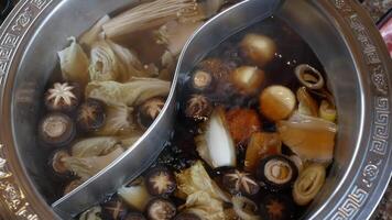 cerca arriba de personas comiendo juntos utilizando palillos poniendo vegetal y carne dentro el estofado rojo picante hirviendo chino Sichuan estilo sopa video