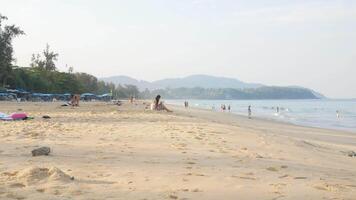 människor turist avkopplande på semester Semester sommar tid på de vit sand strand hav sida på tropisk ö av phuket, naturligt hav landskap i solig dag i 4k video