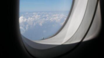 Aerial view through plane window with view over puffy white cloud with clear blue sky while flying, View from the window of the plane traveling by air video