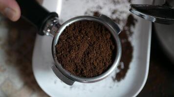 dichtbij omhoog naar hand- gebruik makend van koffie knoeien postzegel in koffie filterhouder emmer vol met geaard koffie Boon naar maken espresso voor ochtend- heet drank drinken video