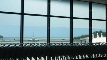 Landscape view from inside departure terminal hall area to outside at aircraft airplane parking area with planes operating in rush hour video